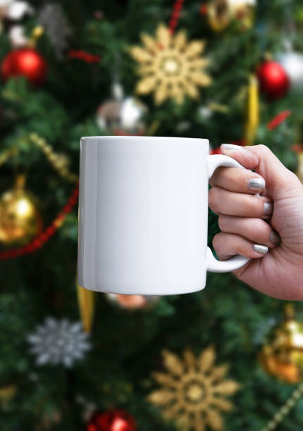 istock women hand holding white ceramic coffee cup on christmas tree background. mockup for creative advertising text message or promotional content. 1189979110