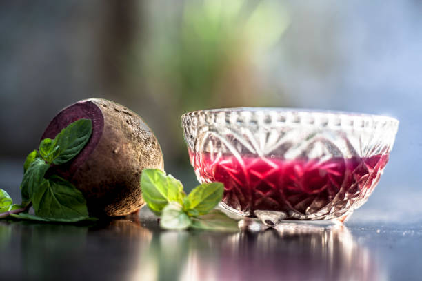 Detoxifying Beetroot extracted tincture in a glass bowl on black glossy surface with some raw fresh sliced beetroot vegetable with it used as a remedy for Inflammation in the kidney. Horizontal shot. desintoxicante de la remolacha extraída tintura en un tazón de vidrio sobre la superficie brillante negro con algún vegetal de remolacha en rodajas frescas crudas con que se utiliza como un remedio para la inflamación en el riñón. disparo horizontal.