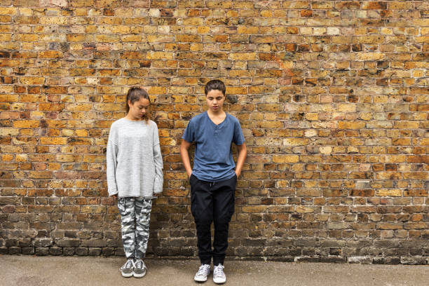istock Two depressed young teens stand in front of a brick wall 1189980862