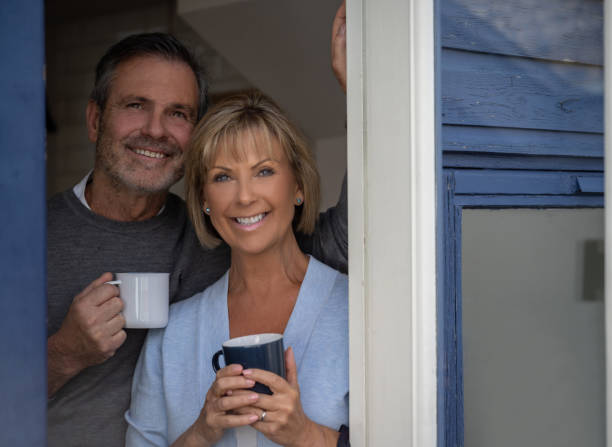 istock Happy couple at home drinking coffee and looking through the window 1189981483