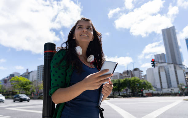 istock Beautiful female student using a mobile app on smartphone while walking at the street smiling 1189981545