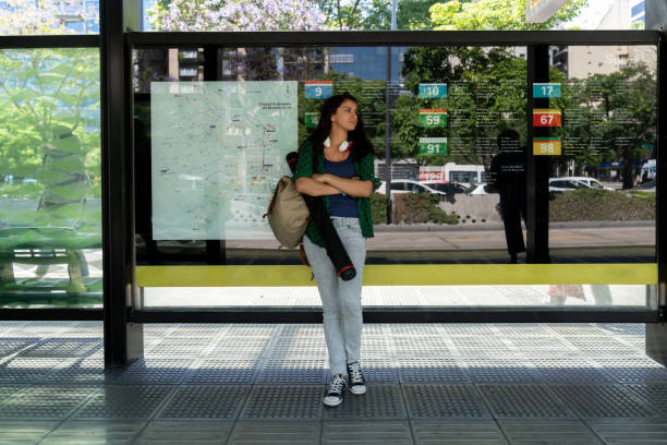 Latin american student at the bus stop waiting - City lifestyles Latin american beautiful student at the bus stop waiting - City lifestyles bus shelter stock pictures, royalty-free photos & images