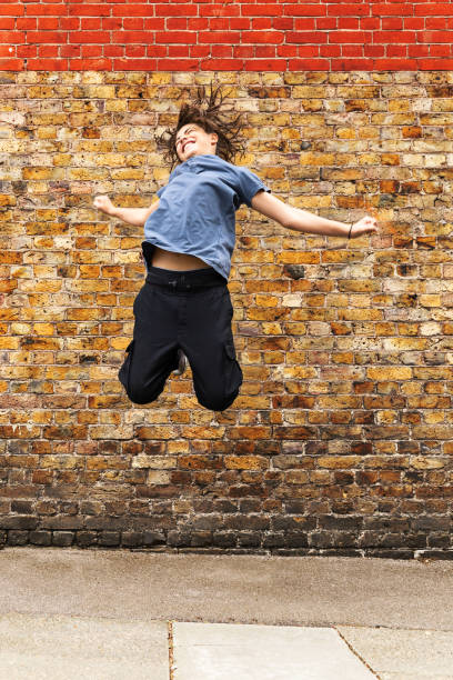 istock Young boy jumps in front of a brown brick wall 1189981604