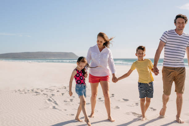 istock Smiling family walking on a sandy beach in summer 1189983105