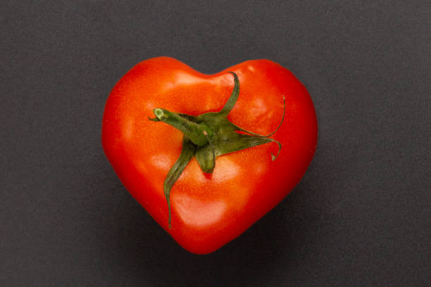 istock Red heart shaped tomato on a black background 1189983332