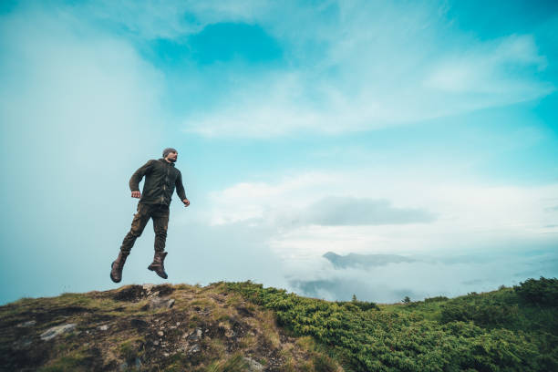 istock The man jumping on the mountain on a beautiful clouds background 1189984314