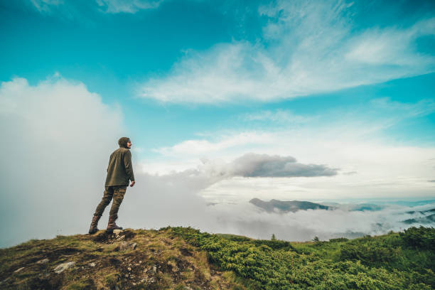 istock The man standing on the mountain on a beautiful clouds background 1189984334