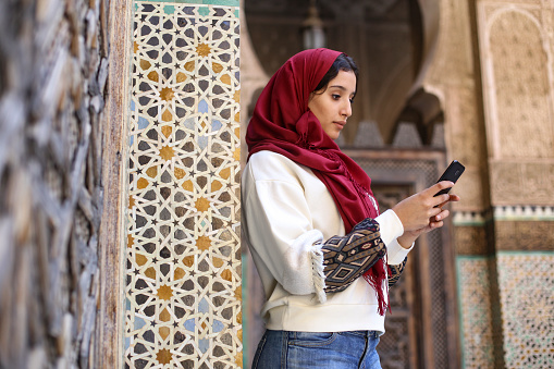 Arab woman in traditional clothing texting on mobile phone. About 25 years old, Middle Eastern female.