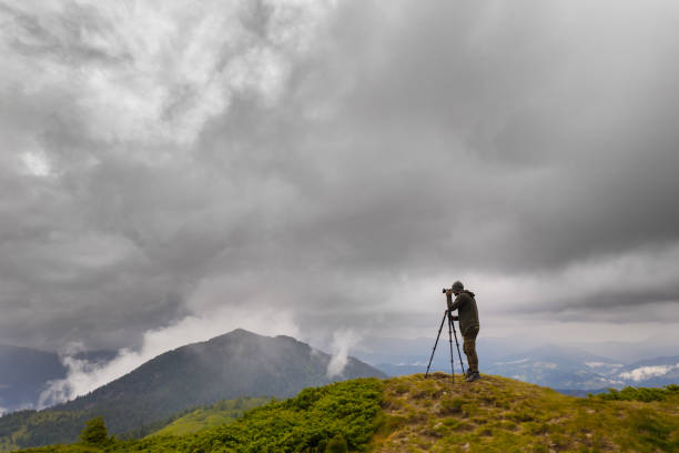 istock The photographer standing on the mountain with rainy clouds 1189985017