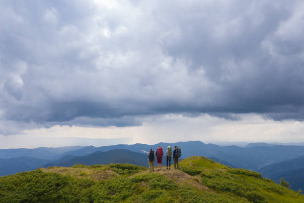 istock The four active people standing on the mountain against beautiful clouds 1189985030