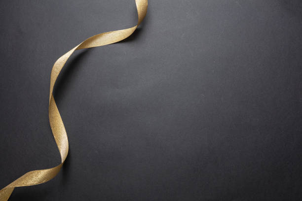 istock Golden ribbon curl on black color background. Minimal card template 1189985302