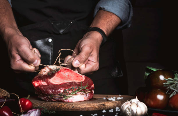 istock Chef cooks beef shank with herbs. 1189986683