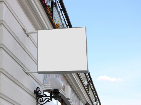 Blank white square sign on wall mock up, sky background. Empty coffeeshop or confectionery display wal mounted mockup. Clear flowershop signpost for advert mokcup template.