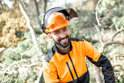 Portrait of a cheerful lumberman in protective workwear resting after the hard work in the forest