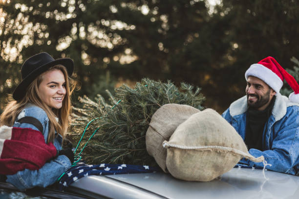 istock Young couple is packing Christmas tree on the car 1189988106