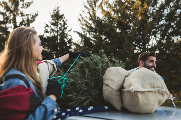 istock Young couple is packing Christmas tree on the car 1189988604