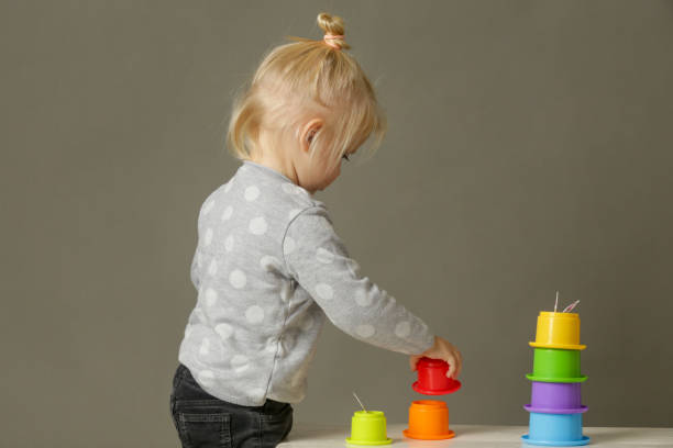istock Studio shot of a toddler playing with colorful plastic cups, motor skill development. These activities for toddlers will get little hands and fingers ready for later-developing skills. 1189988780