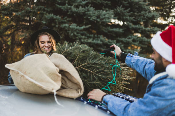istock Young couple is packing Christmas tree on the car 1189988834