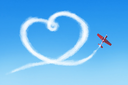 Plane in the sky draws a smoke heart