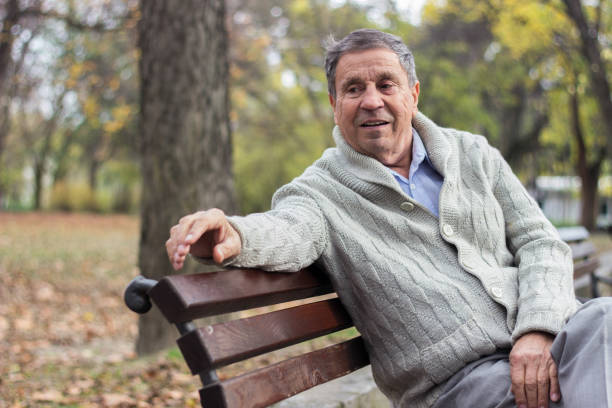 istock Senior man sitting on bench in the park 1189988958