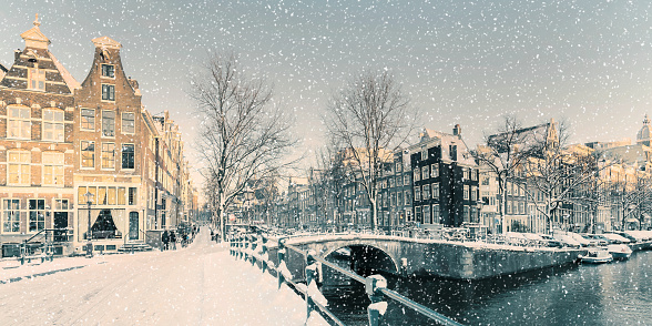 Winter snow view of Dutch canal and old houses in the historic city of Amsterdam