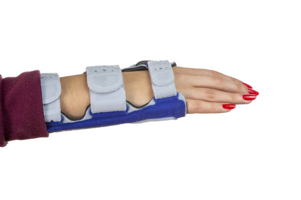 Hand with red painted fingernails and a wrist brace on a white background.