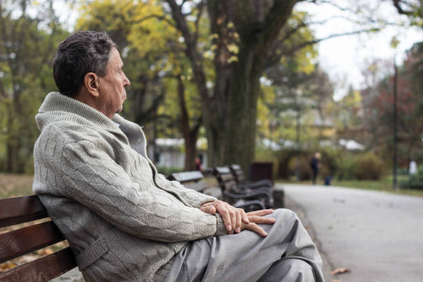 istock Senior man sitting on bench in the park 1189990154