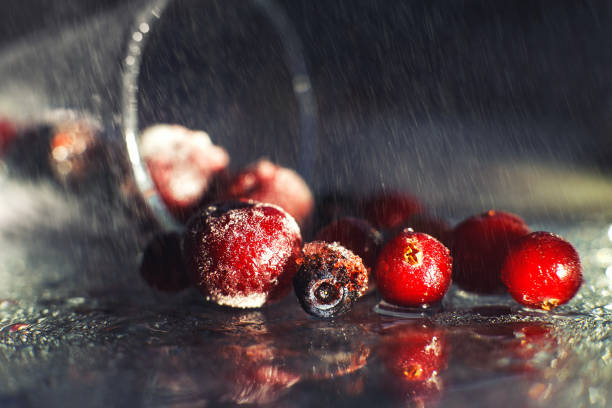 closeup frozen berries on the glass with reflection . frozen berries  on a dark background macro. cranberries blueberries and cherries