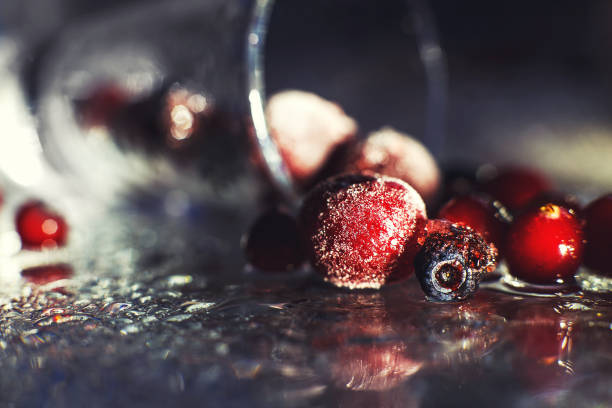 closeup frozen berries on the glass with reflection . frozen berries  on a dark background macro. cranberries blueberries and cherries
