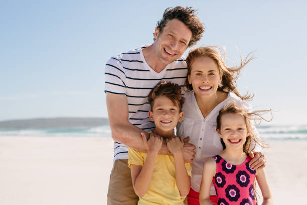 istock Smiling family standing together on a sandy beach 1189994162