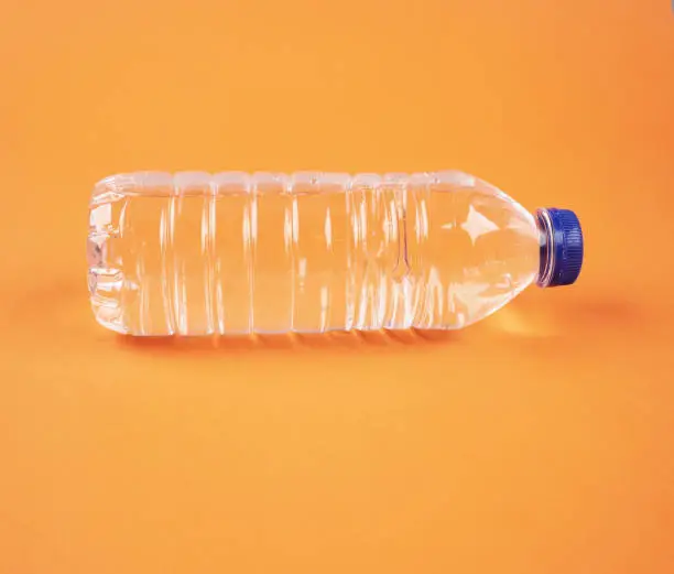 Photo of Water in plastic bottle on isolated orange background