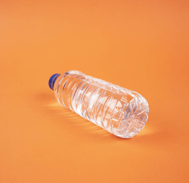 istock Water in plastic bottle on isolated orange background 1190000368