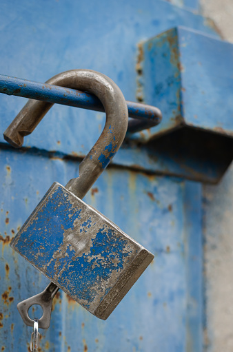 An open padlock with a key in a keyhole. Eye level shooting. Soft focus. Close-up. Portrait version of the photo