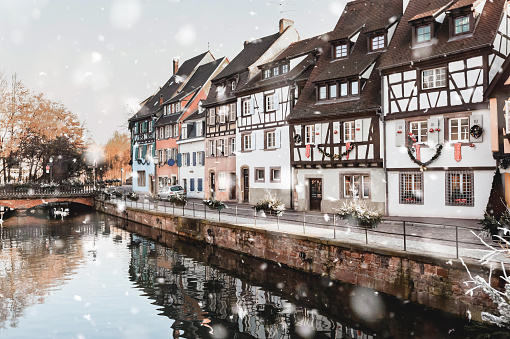 Colmar, France in winter snowstorm. Historical buildings along canal in the city center in snowy weather. Magic Christmas mood. Monochromatic neutral tones with natural light