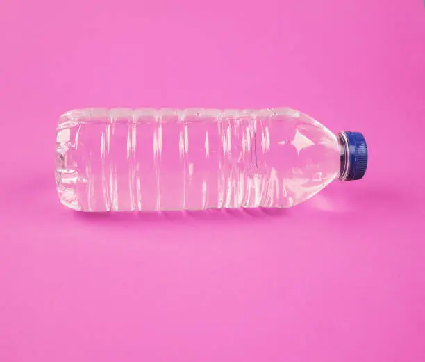 Photo of Water in plastic bottle on isolated pink background
