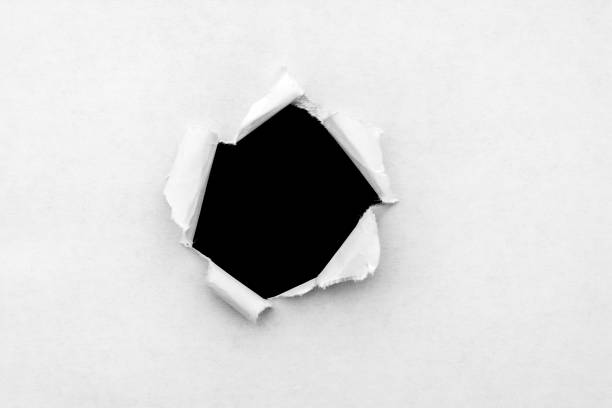 istock A round hole in white paper with torn edges and a black isolated background inside. 1190001854