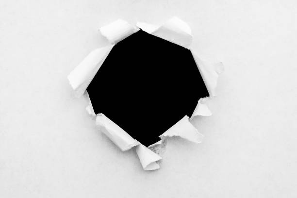 istock A round hole in white paper with torn edges and a black isolated background inside. 1190001858