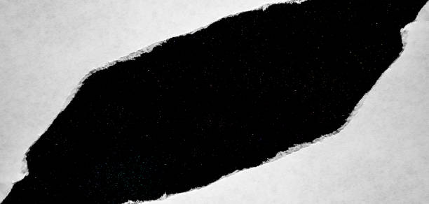 istock A hole in paper with torn edges close-up with a black background inside with colorful space stars in the universe. A hole in paper with a view of the cosmos of the universe. 1190003831