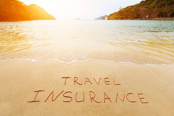 Travel insurance and cover of accidental risk concept. Handwriting drawing on sand. Scenic view on beautiful summer tropical beach of harbor. stock photo