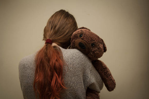 istock Sad girl with teddy bear standing in the corner. 1190007094
