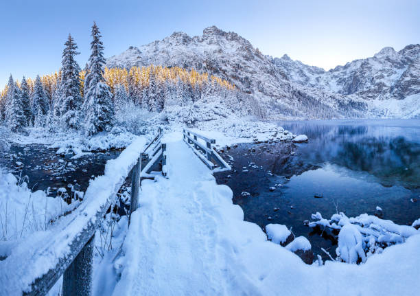 istock Wooden bridge covered with snow on mountain lake 1190009366