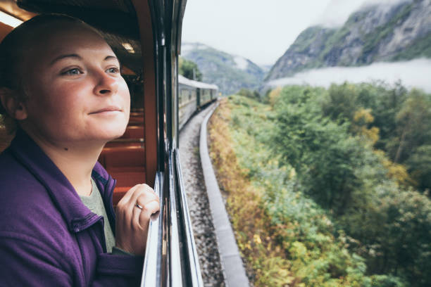 Woman enjoying a ride and looking out the window on Flamsbana mountain railway in Flam, Norway stock photo