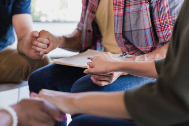istock Diverse group of adults sitting in circle holding hands 1190011885