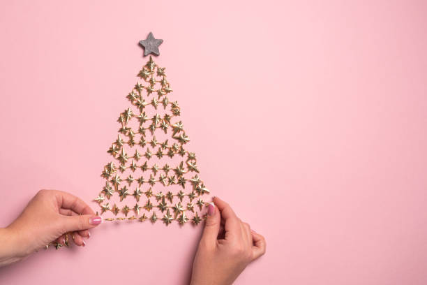 flache lagen der hände machen goldenen weihnachtsbaum mit stern auf rosa papier - christmas tree bead humor stock-fotos und bilder