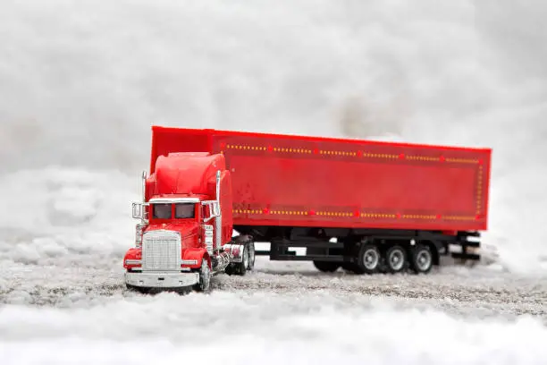 Festive truck in red. toy car rides on the background of real snowdrifts. Winter. Christmas holidays.
