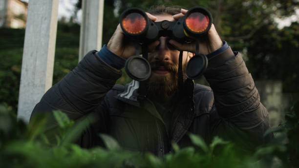istock Young bearded man with long hair looking through binoculars in forest 1190017148