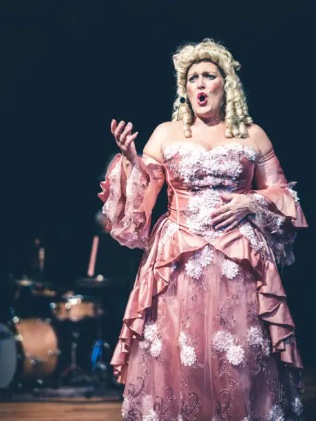 Opera singer performing on the stage  of the alternative art club. She is wearing period costume.