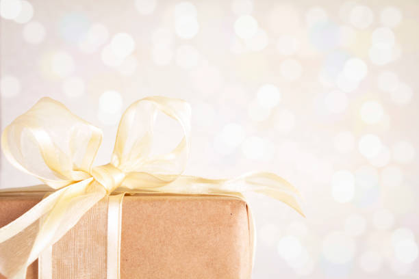 Gift box tied with a gold ribbon, on a defocused background.
