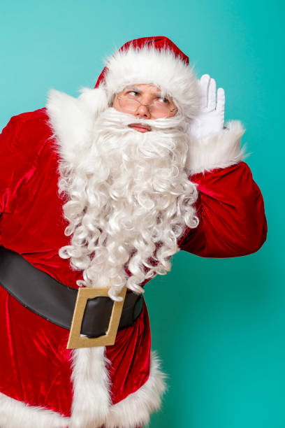 istock Santa holding hand next to ear listening 1190026410