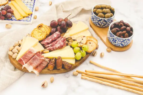 Cheese board brunch for a party with pistachios, olives, grapes and dates